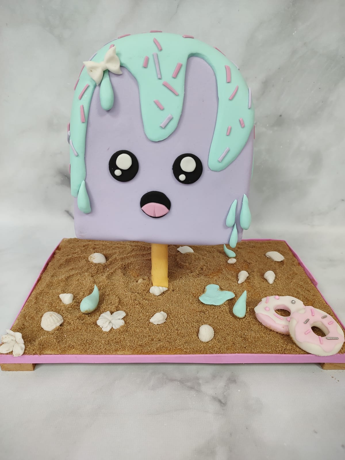 Torta decorada con un diseño divertido en tonos celeste y lila, realizada por Jor.